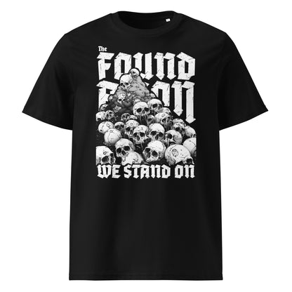 Vorderansicht eines schwarzen T-Shirts mit dem Motiv 'The Foundation We Stand On': Ein großer Haufen aus realistisch gezeichneten Totenschädeln bildet die Basis für einen massiven, weißen Schriftzug in einer modernen Gothic-Schriftart.